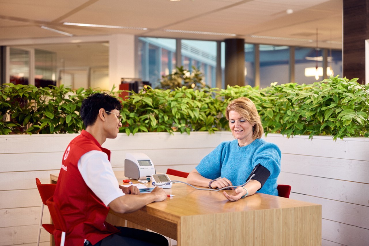 Medewerker Medigo meet bloeddruk op Hartcheckpunt van de Hartstichting